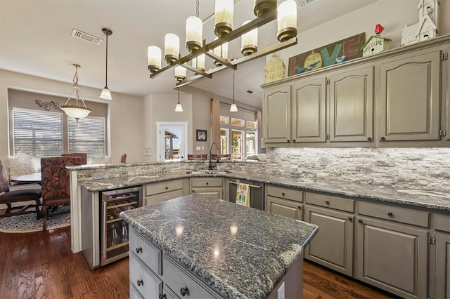 kitchen featuring hanging light fixtures, wine cooler, a kitchen island, stainless steel dishwasher, and dark hardwood / wood-style floors