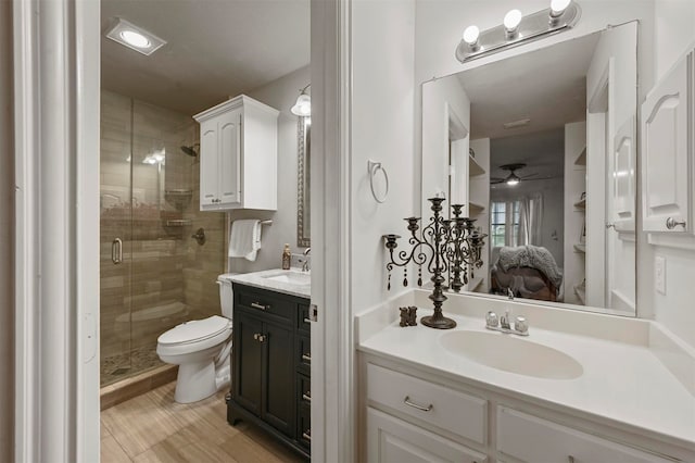 bathroom featuring ceiling fan, an enclosed shower, vanity, and toilet