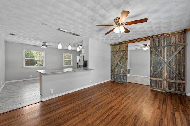 unfurnished living room featuring a barn door and dark wood-type flooring