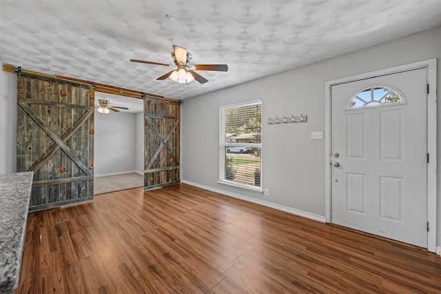 entrance foyer featuring wood-type flooring, a barn door, and a healthy amount of sunlight