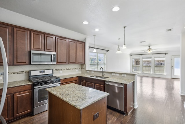 kitchen featuring a center island, appliances with stainless steel finishes, decorative light fixtures, and sink