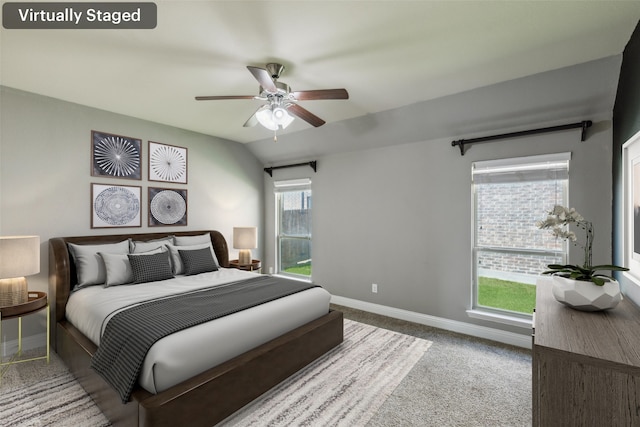 carpeted bedroom with ceiling fan, vaulted ceiling, and multiple windows