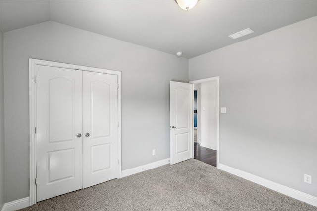 unfurnished bedroom with vaulted ceiling, a closet, and carpet flooring