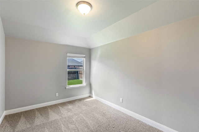 carpeted spare room with lofted ceiling