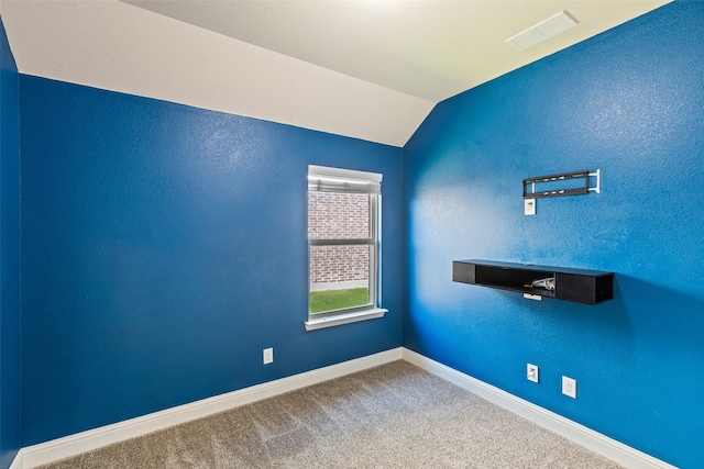 carpeted spare room with lofted ceiling