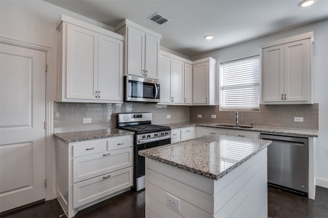 kitchen with a kitchen island, white cabinetry, sink, and stainless steel appliances