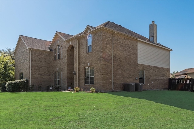 rear view of house with a yard and cooling unit