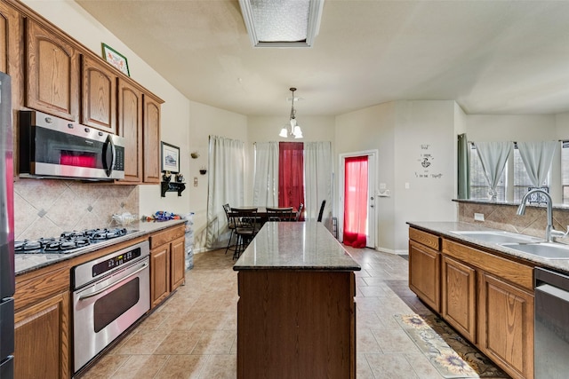 kitchen featuring decorative backsplash, stainless steel appliances, sink, pendant lighting, and a kitchen island