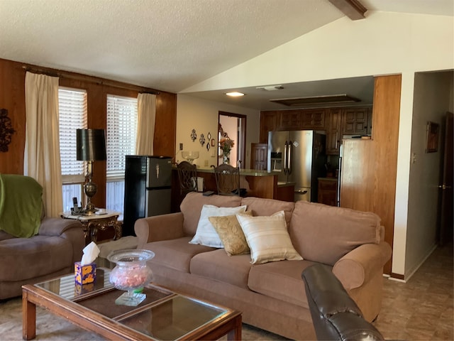 living room with a textured ceiling and vaulted ceiling with beams