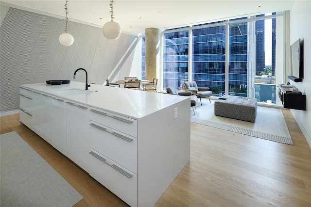 kitchen with white cabinets, decorative light fixtures, sink, and a wealth of natural light