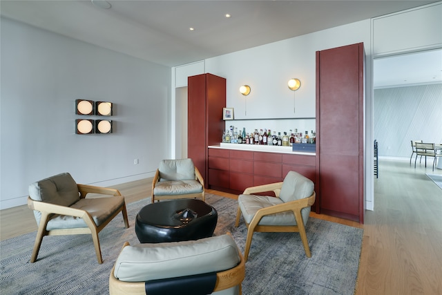 sitting room with bar and light hardwood / wood-style floors