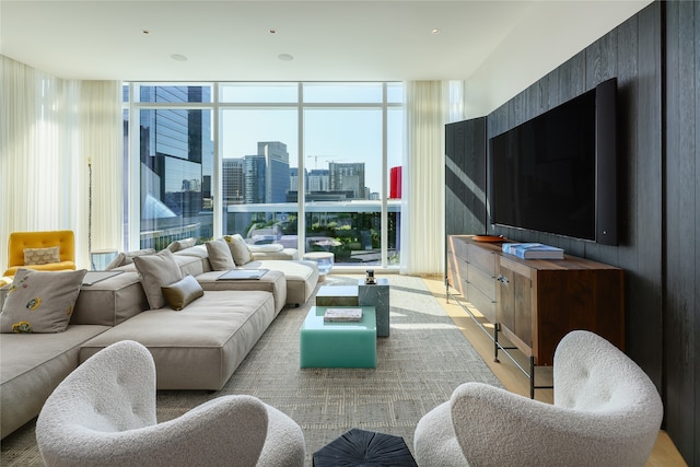 living room with light wood-type flooring, a wall of windows, and a healthy amount of sunlight