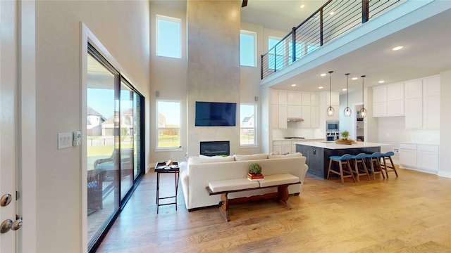 living room with a fireplace, plenty of natural light, a high ceiling, and light wood-type flooring