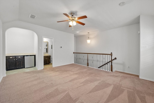 empty room with ceiling fan, light carpet, and vaulted ceiling