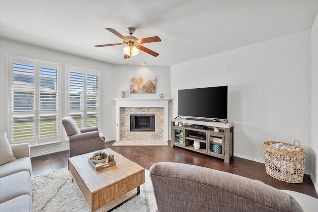 living room with a brick fireplace, dark hardwood / wood-style flooring, and ceiling fan