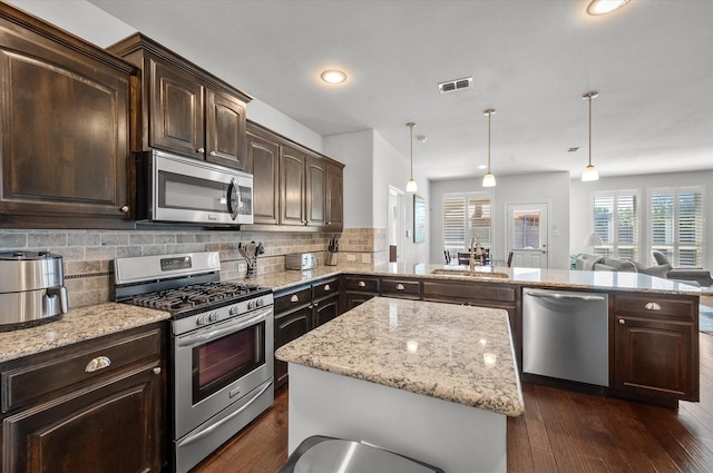 kitchen featuring tasteful backsplash, sink, stainless steel appliances, and pendant lighting