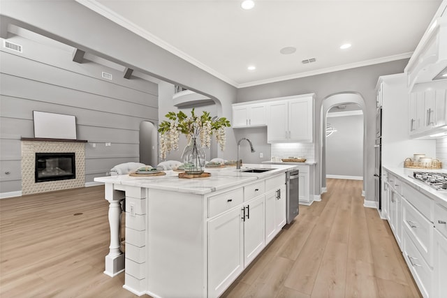 kitchen with a kitchen island with sink, light wood-type flooring, sink, and white cabinetry