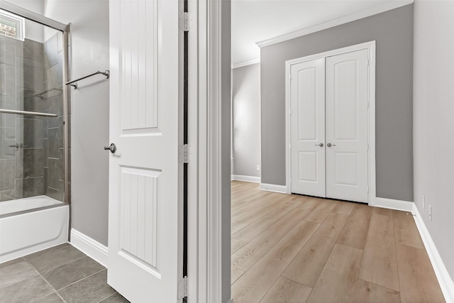 bathroom with bath / shower combo with glass door, hardwood / wood-style flooring, and ornamental molding