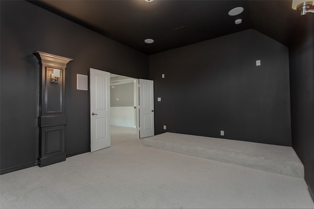 interior space with vaulted ceiling and light colored carpet