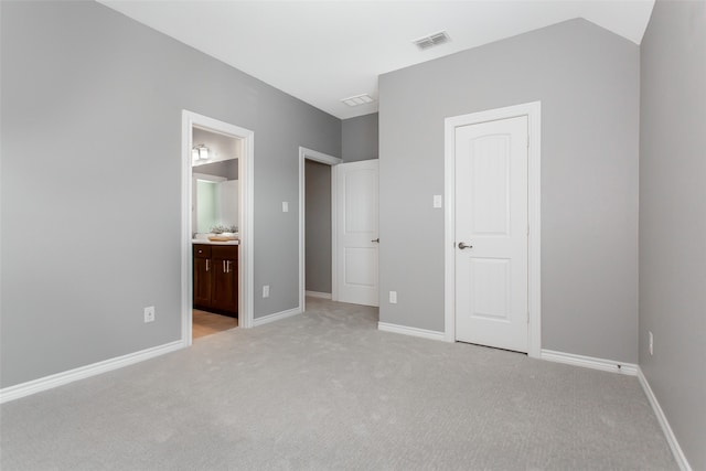 unfurnished bedroom with ensuite bath and light colored carpet