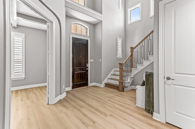 entrance foyer featuring a towering ceiling, light hardwood / wood-style flooring, and a wealth of natural light