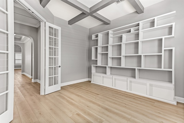 empty room featuring coffered ceiling, ornamental molding, beamed ceiling, and light hardwood / wood-style floors