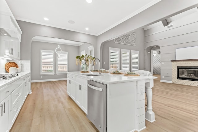 kitchen with a healthy amount of sunlight, stainless steel appliances, white cabinets, and a kitchen island with sink