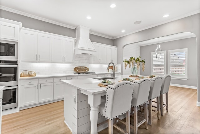 kitchen with custom exhaust hood, light hardwood / wood-style floors, sink, and white cabinetry