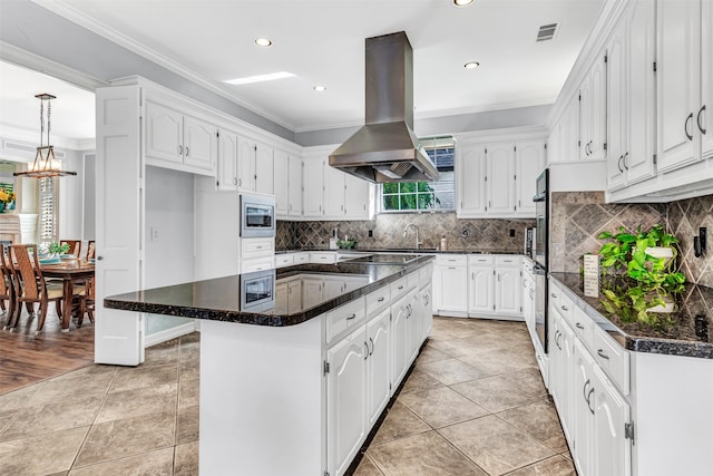 kitchen featuring island range hood, a kitchen island, stainless steel microwave, and white cabinets