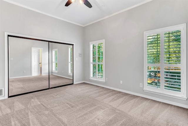 unfurnished bedroom featuring multiple windows, light carpet, ceiling fan, and a closet