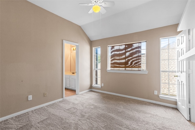 unfurnished bedroom with vaulted ceiling, ensuite bath, ceiling fan, and light colored carpet