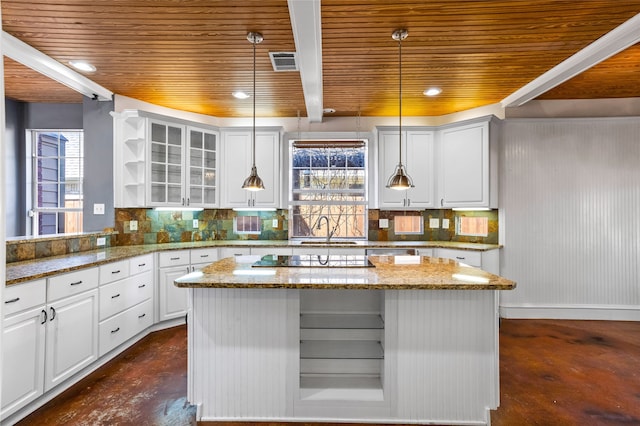 kitchen with hanging light fixtures, white cabinetry, tasteful backsplash, light stone countertops, and sink