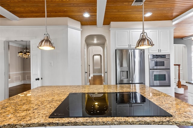 kitchen with light stone counters, white cabinets, an inviting chandelier, stainless steel appliances, and dark hardwood / wood-style flooring