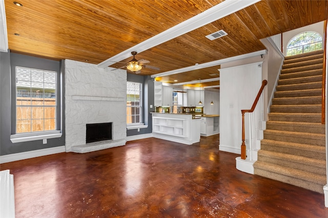 unfurnished living room featuring wooden ceiling, a stone fireplace, and a wealth of natural light