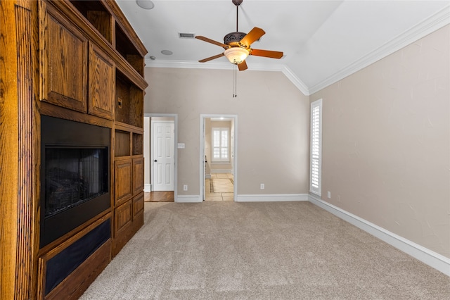 unfurnished living room featuring lofted ceiling, ornamental molding, ceiling fan, and light carpet