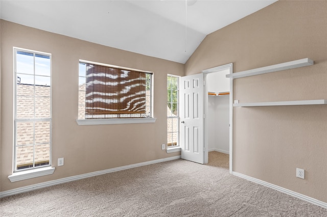 unfurnished bedroom featuring multiple windows, carpet, and lofted ceiling