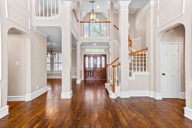 entryway featuring an inviting chandelier, a high ceiling, dark hardwood / wood-style floors, and crown molding