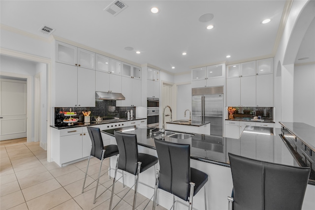 kitchen with stainless steel built in fridge, light tile patterned floors, and white cabinetry