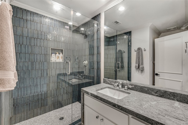 bathroom with a shower with door, vanity, and crown molding