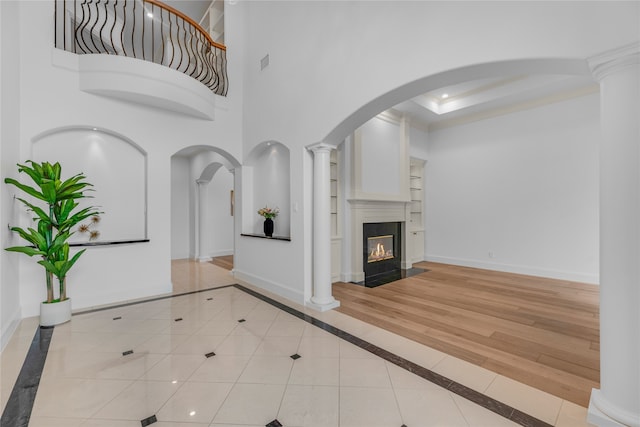 interior space featuring light wood-type flooring, a towering ceiling, and a tray ceiling