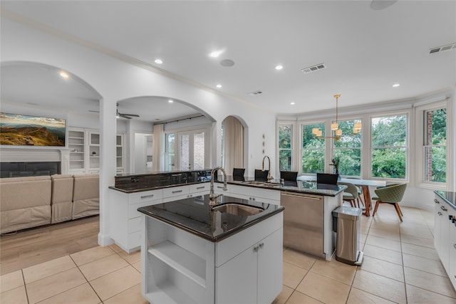 kitchen with an island with sink, white cabinets, pendant lighting, and light tile patterned flooring