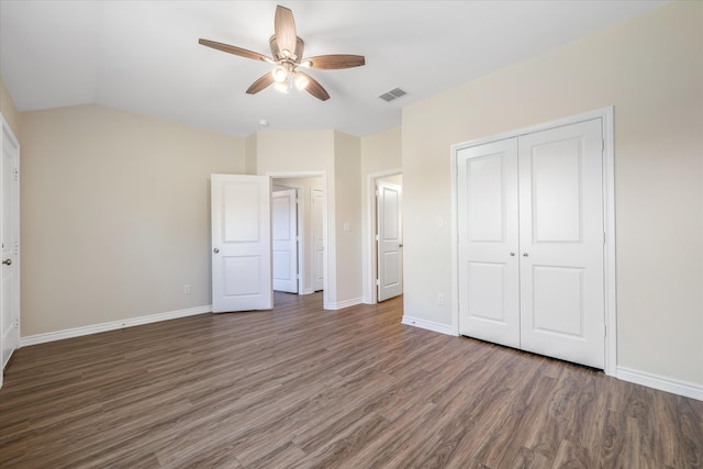 unfurnished bedroom featuring ceiling fan, vaulted ceiling, dark wood-type flooring, and a closet