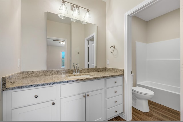 full bathroom featuring hardwood / wood-style floors, vanity, toilet, and bathtub / shower combination