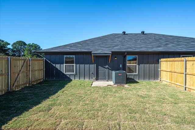 rear view of property with central AC and a lawn