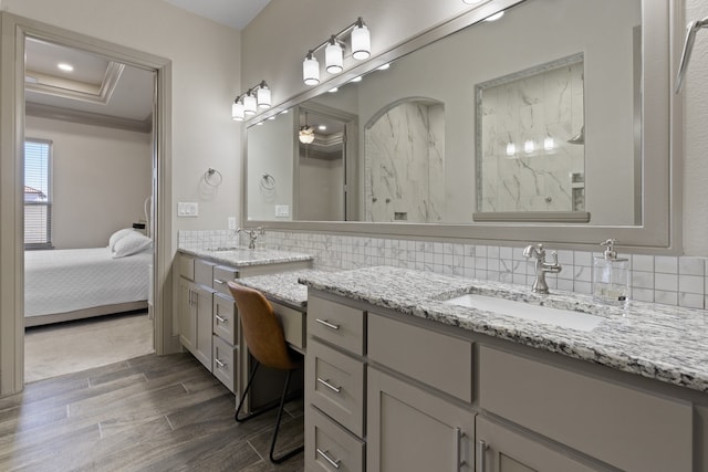 bathroom featuring ornamental molding, wood-type flooring, vanity, a raised ceiling, and decorative backsplash