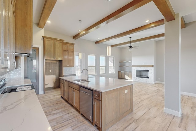 kitchen featuring a kitchen island with sink, light hardwood / wood-style flooring, appliances with stainless steel finishes, beam ceiling, and light stone counters