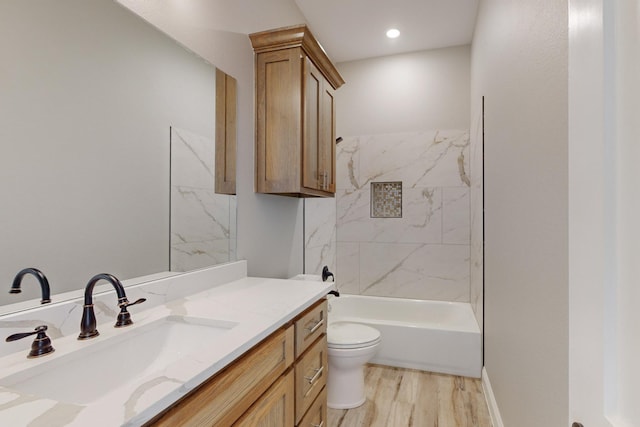 full bathroom with hardwood / wood-style floors, vanity, toilet, and tiled shower / bath