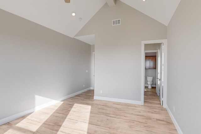 unfurnished room featuring beam ceiling, high vaulted ceiling, and light wood-type flooring