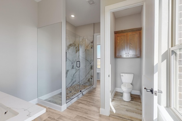 bathroom with hardwood / wood-style floors, a shower with door, and toilet