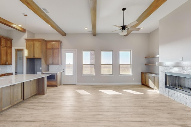 kitchen with ceiling fan, light wood-type flooring, a fireplace, tasteful backsplash, and beam ceiling